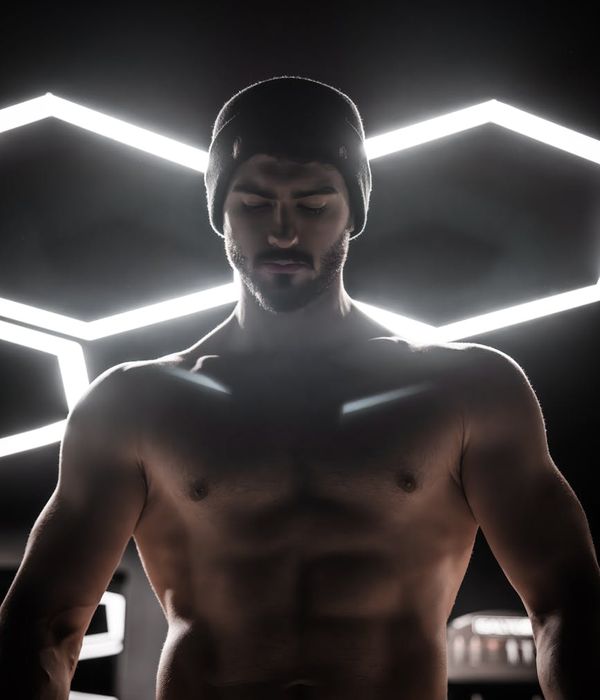 Man performing a strength exercise in a modern gym with focused lighting.